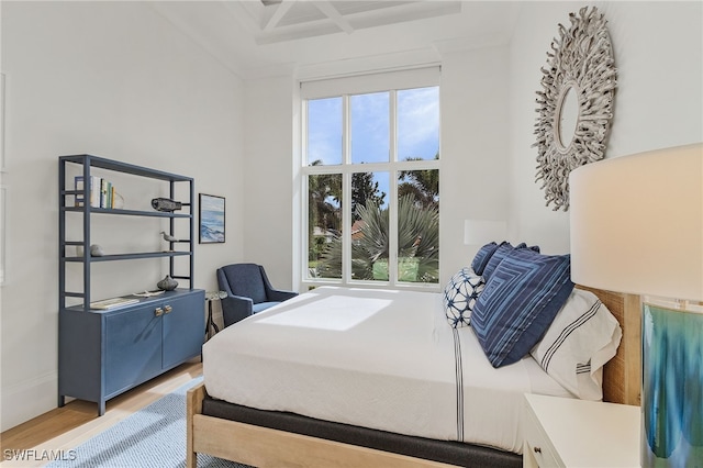 bedroom with multiple windows, coffered ceiling, and light wood-type flooring