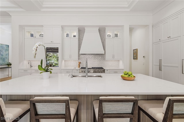 kitchen with white cabinetry, a large island, a breakfast bar, and custom exhaust hood