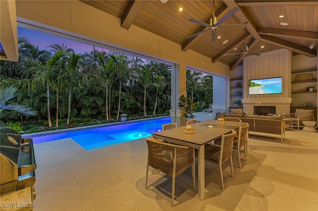 pool at dusk featuring ceiling fan, a patio, and an outdoor fireplace