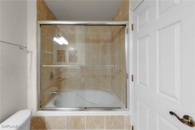 bathroom featuring bath / shower combo with glass door and toilet