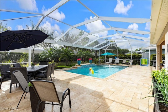 view of pool with glass enclosure, pool water feature, and a patio