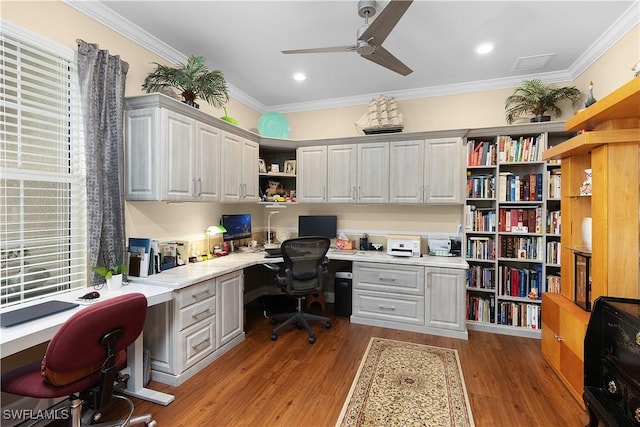 office with ceiling fan, crown molding, built in desk, and light wood-type flooring