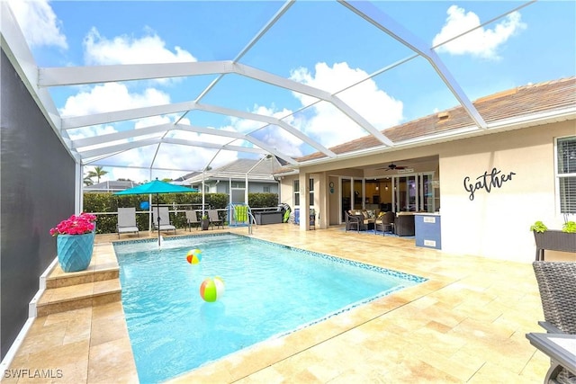 view of swimming pool with glass enclosure, ceiling fan, and a patio