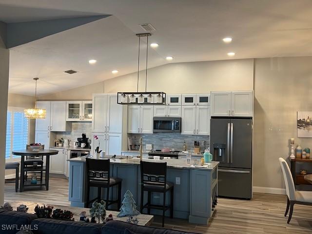 kitchen featuring white cabinets, an island with sink, pendant lighting, and appliances with stainless steel finishes