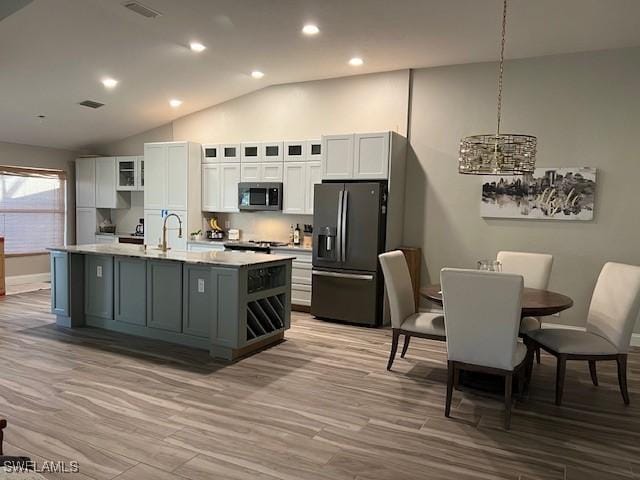 kitchen with white cabinetry, sink, decorative light fixtures, a center island with sink, and appliances with stainless steel finishes