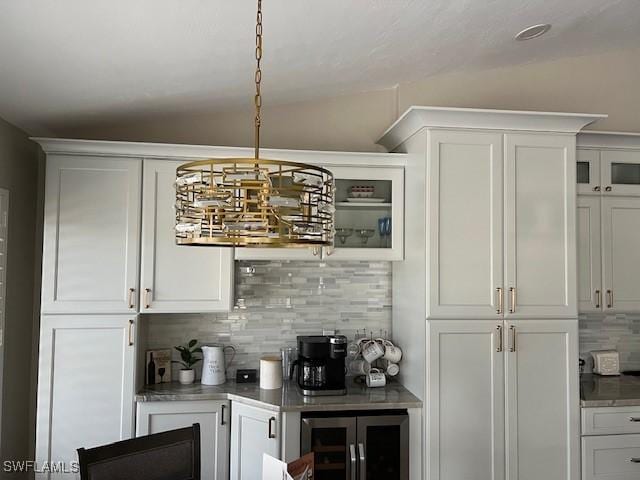 bar with backsplash, hanging light fixtures, vaulted ceiling, white cabinetry, and beverage cooler