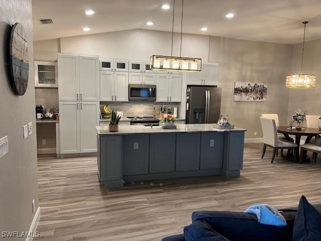 kitchen featuring a center island with sink, decorative light fixtures, white cabinets, and stainless steel appliances