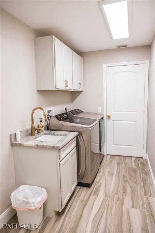 clothes washing area featuring cabinets, sink, washer and clothes dryer, and a skylight