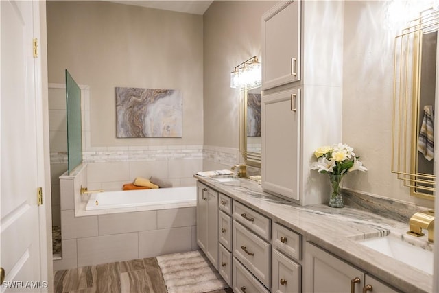 bathroom featuring vanity and tiled bath