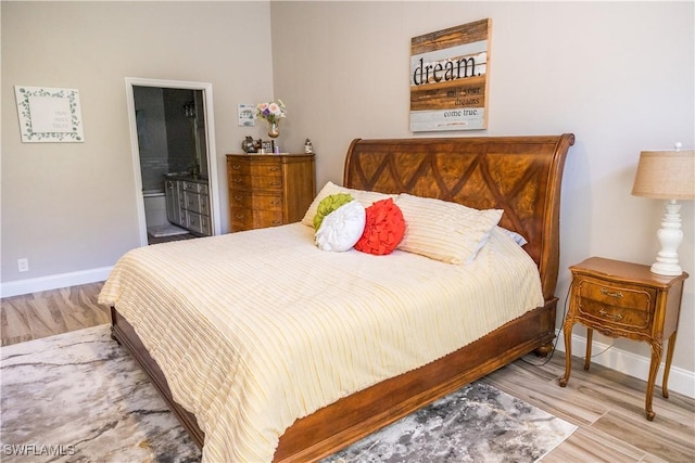 bedroom featuring connected bathroom and light hardwood / wood-style floors