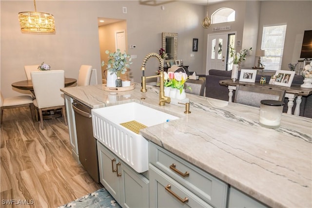 kitchen with hanging light fixtures, gray cabinets, light stone countertops, and sink