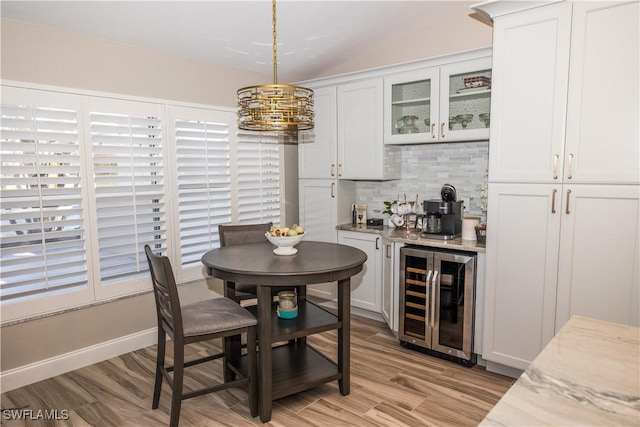 dining space with indoor bar, beverage cooler, and light wood-type flooring