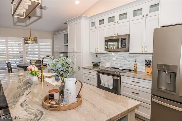 kitchen with pendant lighting, white cabinetry, stainless steel appliances, tasteful backsplash, and light stone countertops