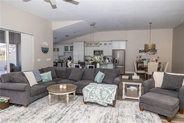 living room featuring ceiling fan, lofted ceiling, and light wood-type flooring