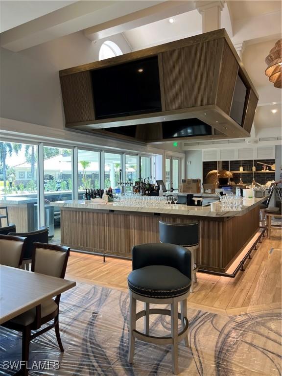 bar featuring high vaulted ceiling and light wood-type flooring