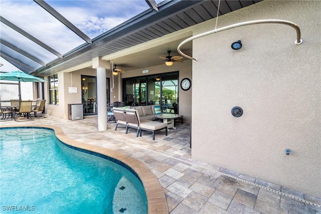 view of swimming pool with a patio area, outdoor lounge area, ceiling fan, and glass enclosure