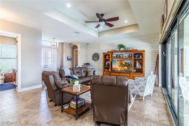 living room featuring ceiling fan and a raised ceiling