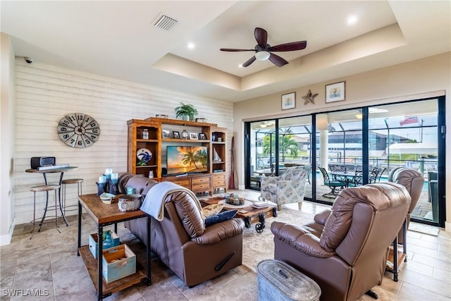 living room with ceiling fan and a tray ceiling