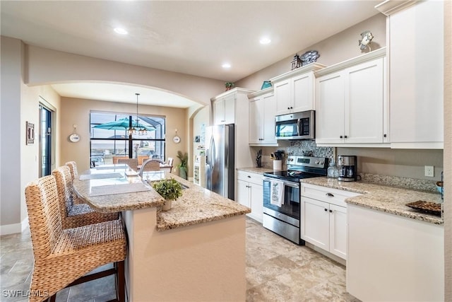 kitchen with pendant lighting, appliances with stainless steel finishes, a breakfast bar, and an island with sink