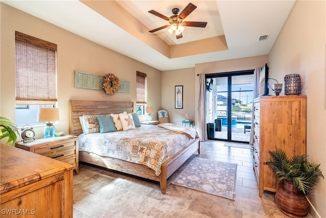 bedroom featuring access to outside, a raised ceiling, and ceiling fan