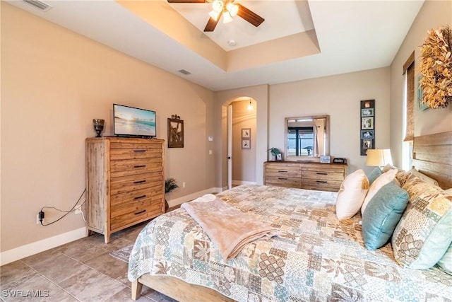 tiled bedroom with a tray ceiling and ceiling fan