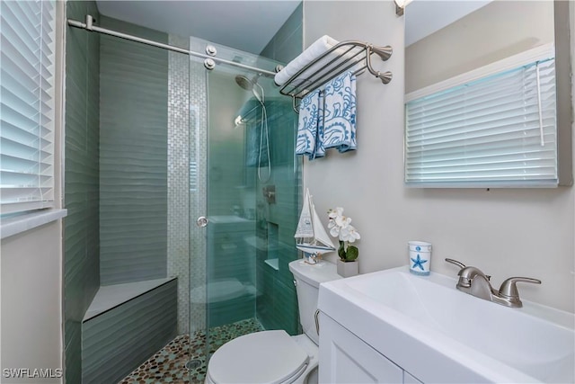 bathroom featuring vanity, a shower with shower door, and toilet