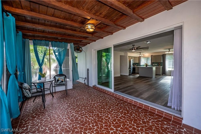 unfurnished sunroom featuring ceiling fan, beamed ceiling, and wood ceiling