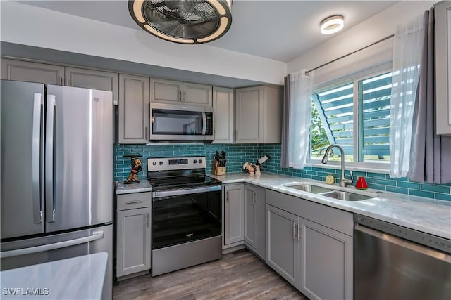 kitchen with decorative backsplash, stainless steel appliances, gray cabinets, and sink