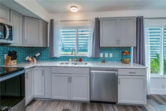 kitchen with backsplash, gray cabinetry, stainless steel appliances, sink, and hardwood / wood-style flooring