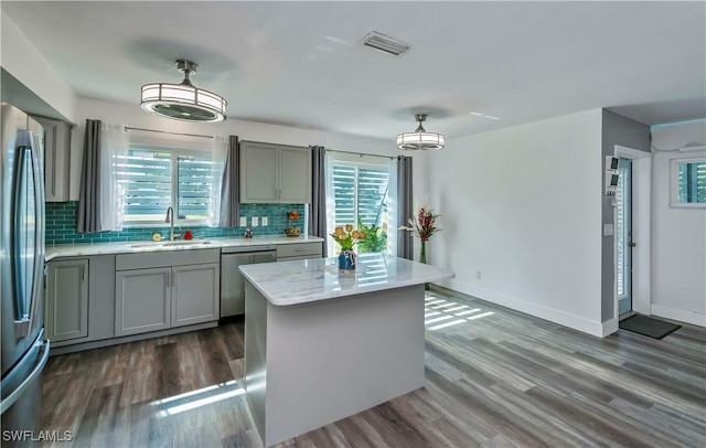 kitchen featuring sink, hanging light fixtures, stainless steel appliances, decorative backsplash, and a kitchen island