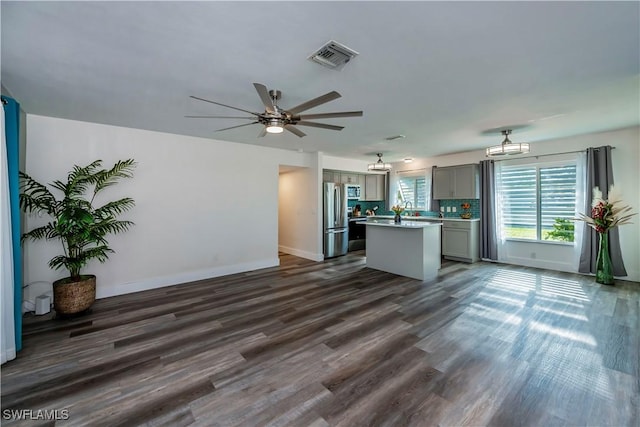 unfurnished living room with ceiling fan, sink, and dark wood-type flooring