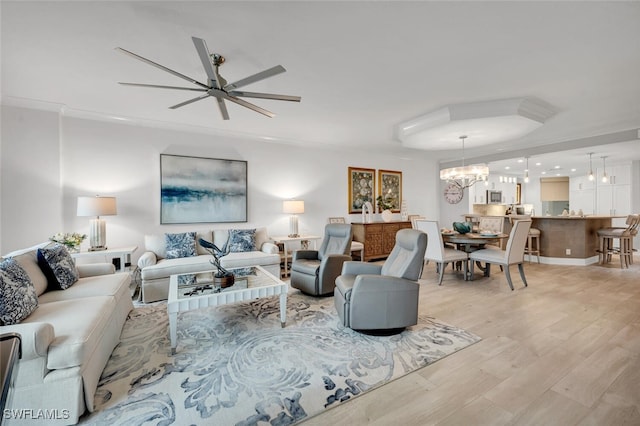 living room with ornamental molding, ceiling fan with notable chandelier, and light hardwood / wood-style flooring