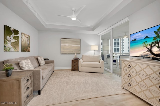 living room with ceiling fan, ornamental molding, and a tray ceiling