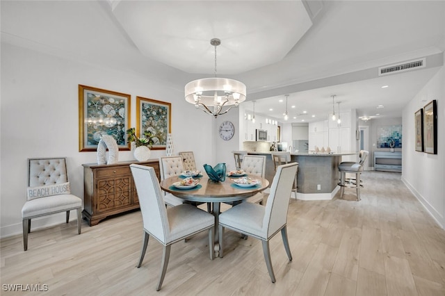 dining space with an inviting chandelier and light hardwood / wood-style flooring