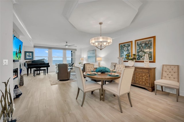 dining area with a water view, ceiling fan with notable chandelier, and light hardwood / wood-style flooring