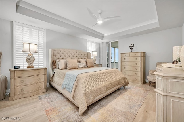 bedroom featuring a raised ceiling, ceiling fan, and light wood-type flooring