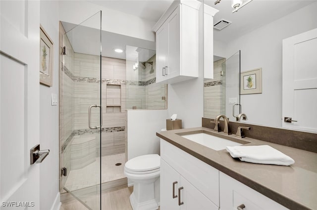 bathroom with vanity, a shower with door, and toilet