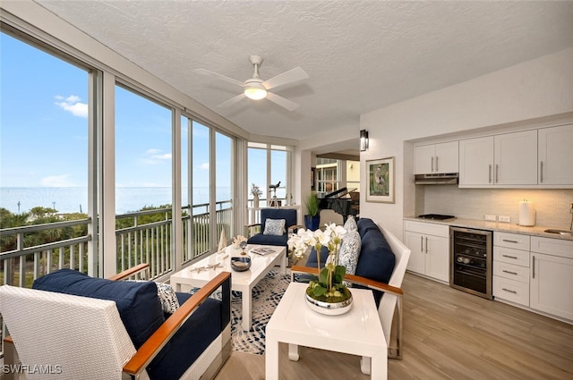 living room featuring plenty of natural light, light hardwood / wood-style floors, beverage cooler, and a water view