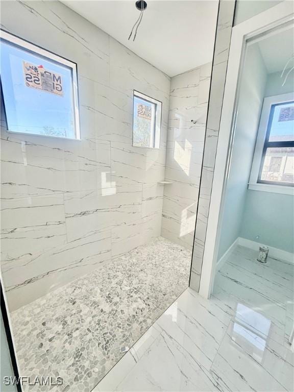 bathroom with a tile shower and a wealth of natural light