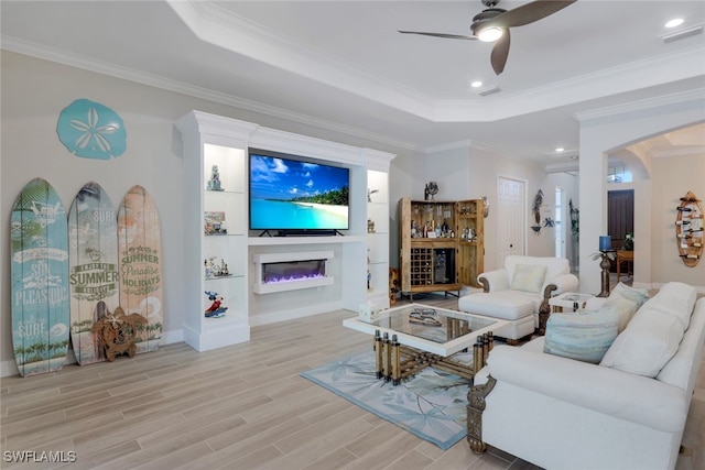 living room featuring a raised ceiling, light hardwood / wood-style floors, and ornamental molding