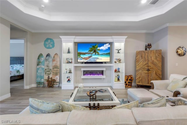 living room with a raised ceiling, light wood-type flooring, and crown molding