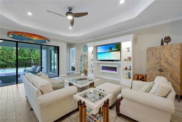 living room with a raised ceiling, ceiling fan, and crown molding