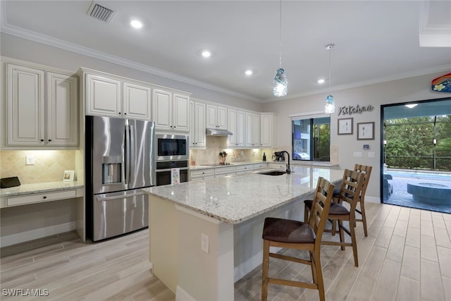 kitchen featuring visible vents, under cabinet range hood, light wood-type flooring, appliances with stainless steel finishes, and a sink