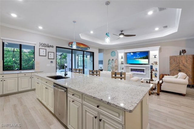 kitchen with a sink, a raised ceiling, dishwasher, and open floor plan