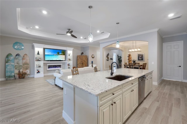 kitchen with dishwasher, arched walkways, a glass covered fireplace, a raised ceiling, and a sink