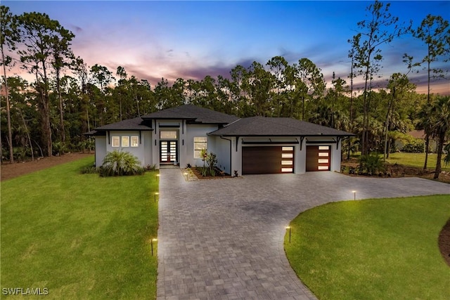 prairie-style home featuring a garage, a yard, and french doors