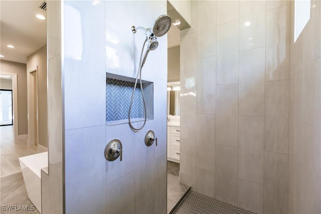 bathroom with tiled shower and vanity