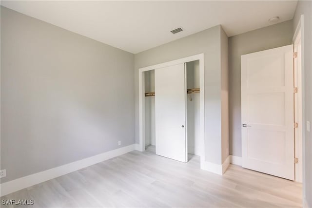 unfurnished bedroom with a closet and light wood-type flooring