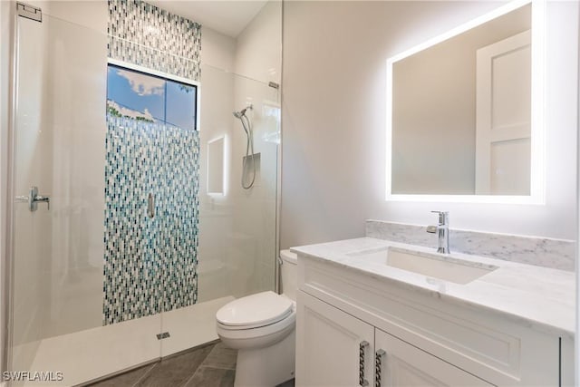 bathroom featuring tile patterned floors, a shower with door, vanity, and toilet