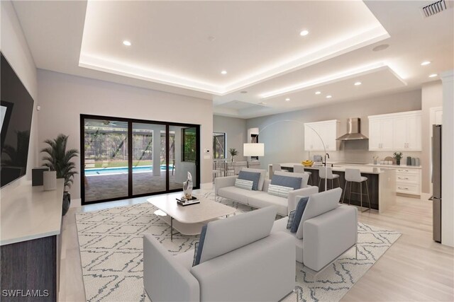 living room featuring a tray ceiling, light hardwood / wood-style flooring, and sink